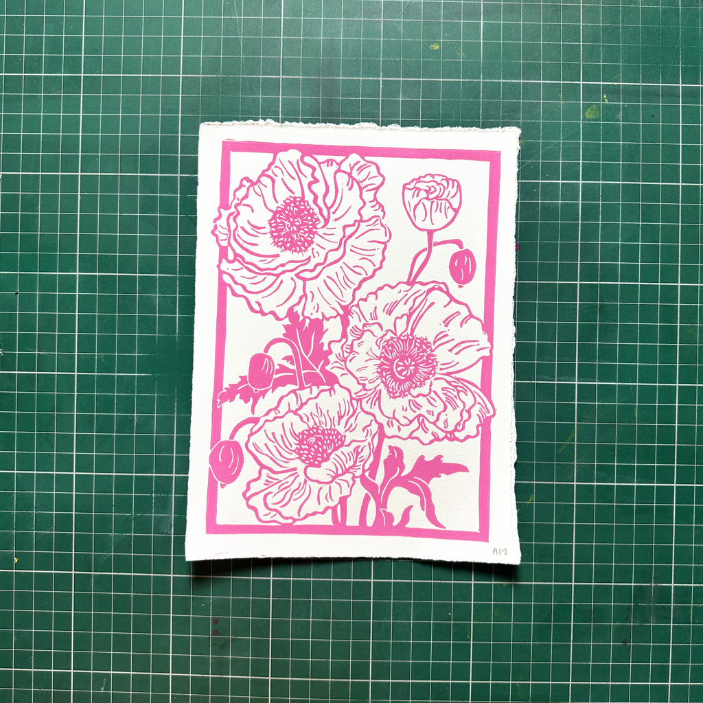 Floral design with pink flowers on a white card, placed on a green grid surface.