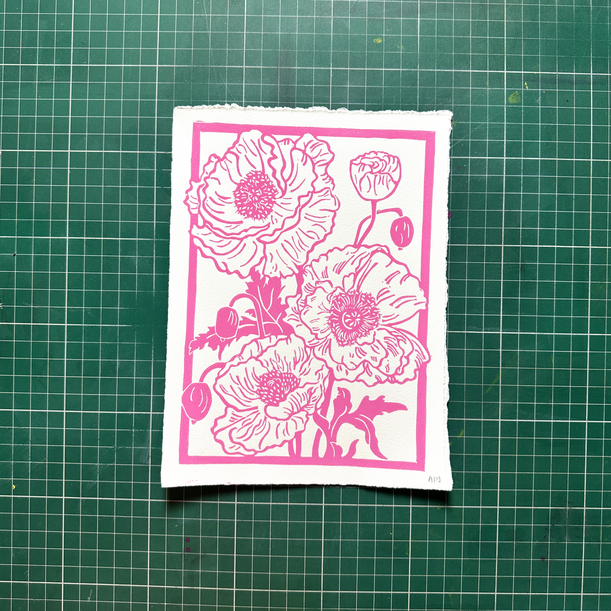 Floral design with pink flowers on a white card, placed on a green grid surface.