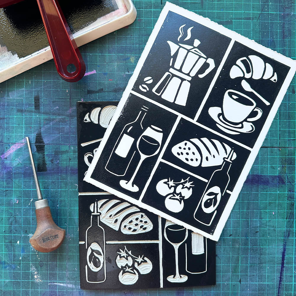 Stencils with food and drink illustrations on a cutting mat with a craft tool.