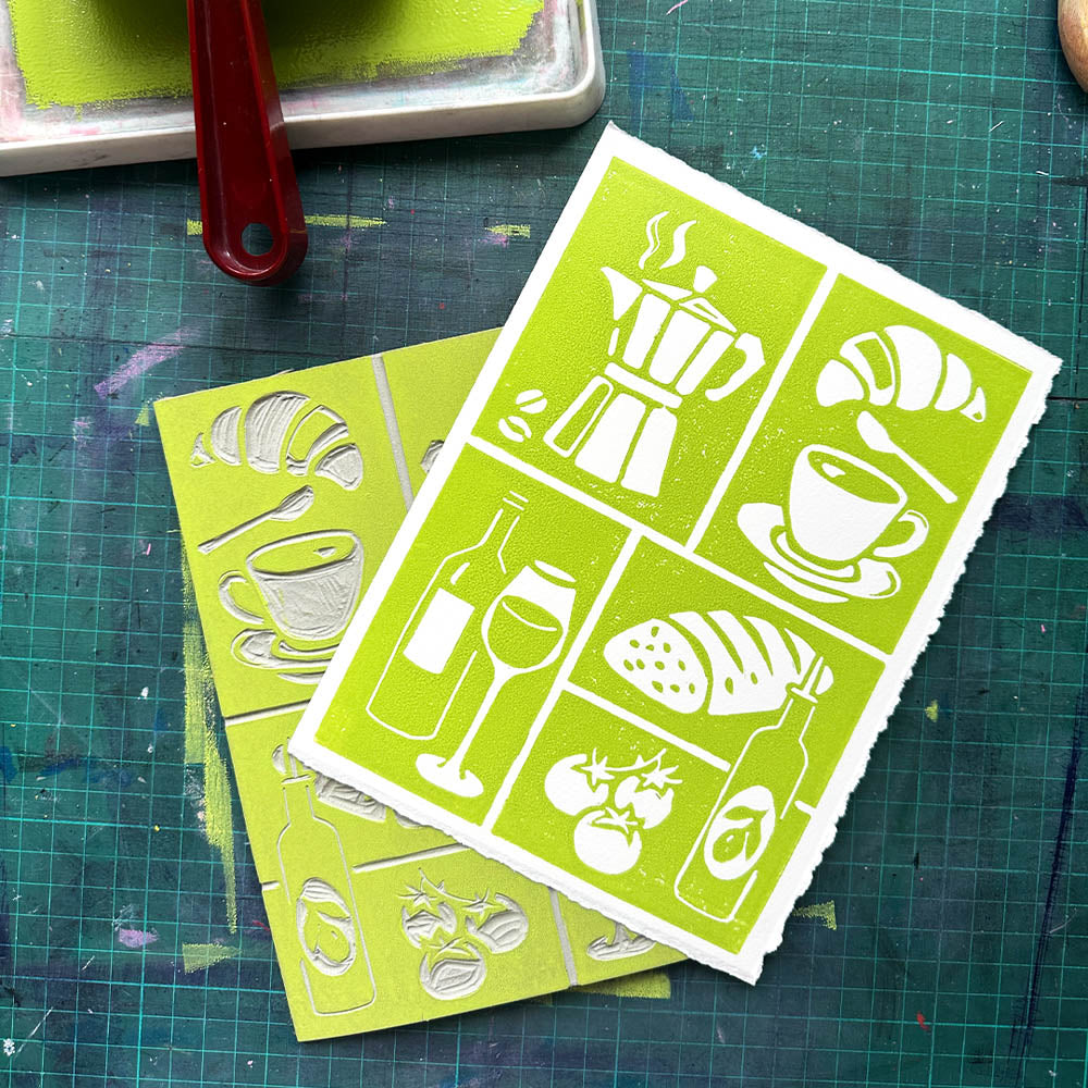 Two green stencils with white designs on a green cutting mat.